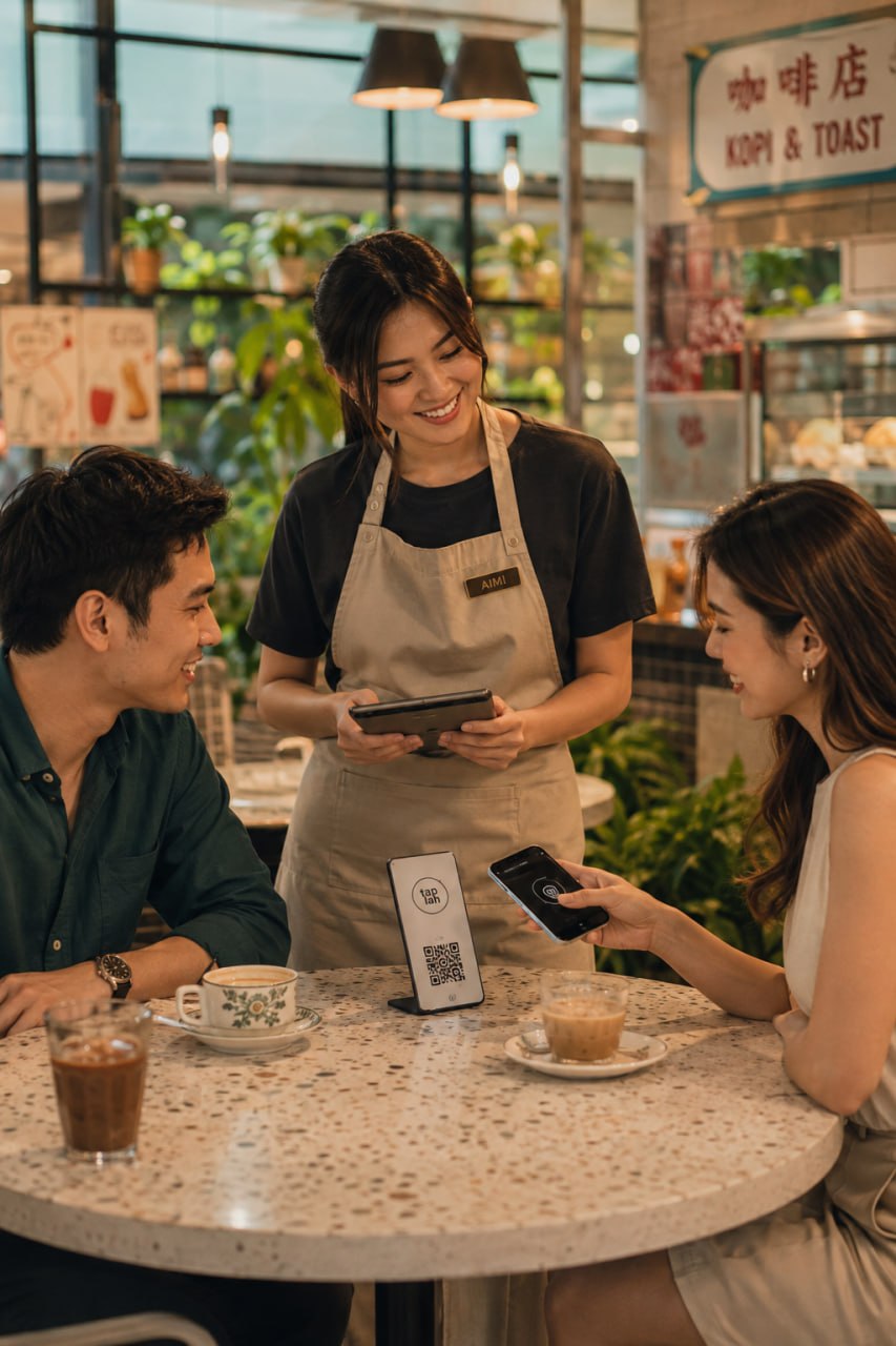Café staff and customers using a Tap-lah stand at the table